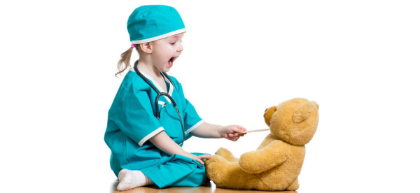 Adorable child dressed as doctor playing with toy over white
