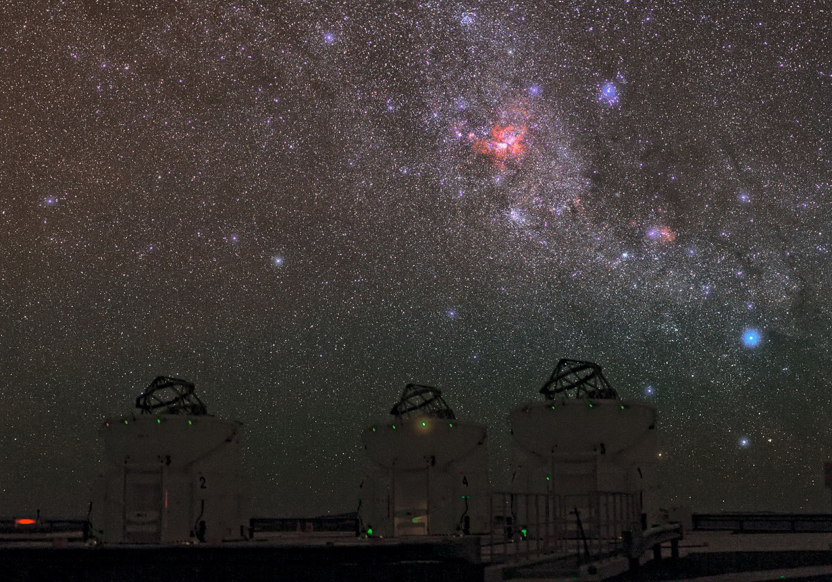 ESO Photo Ambassador, Babak Tafreshi has captured an outstanding image of the sky over ESO’s Paranal Observatory, with a treasury of deep-sky objects. The most obvious of these is the Carina Nebula, glowing intensely red in the middle of the image.  The Carina Nebula lies in the constellation of Carina (The Keel), about 7500 light-years from Earth. This cloud of glowing gas and dust is the brightest nebula in the sky and contains several of the brightest and most massive stars known in the Milky Way, such as Eta Carinae. The Carina Nebula is a perfect test-bed for astronomers to unveil the mysteries of the violent birth and death of massive stars. For some beautiful recent images of the Carina Nebula from ESO, see eso1208, eso1145, and eso1031. Below the Carina Nebula, we see the Wishing Well Cluster (NGC 3532). This open cluster of young stars was named because, through a telescope’s eyepiece, it looks like a handful of silver coins twinkling at the bottom of a wishing well. Further to the right, we find the Lambda Centauri Nebula (IC 2944), a cloud of glowing hydrogen and newborn stars which is sometimes nicknamed the Running Chicken Nebula, from a bird-like shape that some people see in its brightest region (see eso1135). Above this nebula and slightly to the left we find the Southern Pleiades (IC 2632), an open cluster of stars that is similar to its more familiar northern namesake. In the foreground, we see three of the four Auxiliary Telescopes (ATs) of the Very Large Telescope Interferometer (VLTI). Using the VLTI, the ATs — or the VLT’s 8.2-metre Unit Telescopes — can be used together as a single giant telescope which can see finer details than would be possible with the individual telescopes. The VLTI has been used for a broad range of research including the study of circumstellar discs around young stellar objects and of active galactic nuclei, one of the most energetic and mysterious phenomena in the Universe. Links ESO Photo Ambassadors