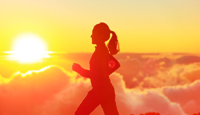 Runner woman running in sunshine sunset. Fitness athlete training trail running marathon in mountains above the clouds in beautiful mountain landscape. Female in jogging in silhouette.