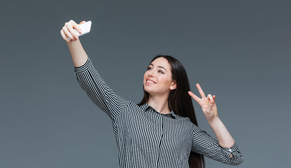 Smiling businesswoman making selfie photo on smartphone  over gray background
