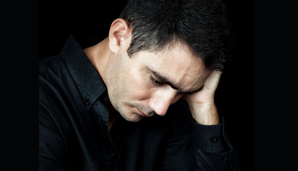 Dramatic close-up of a worried and depressed man isolated on black