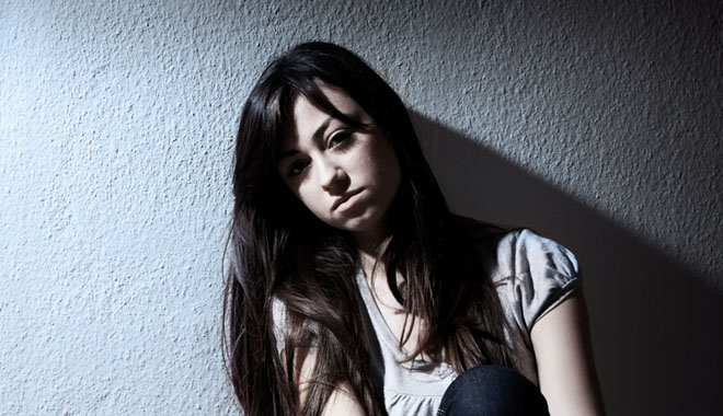 Portrait of depressed teenage girl sitting on floor.