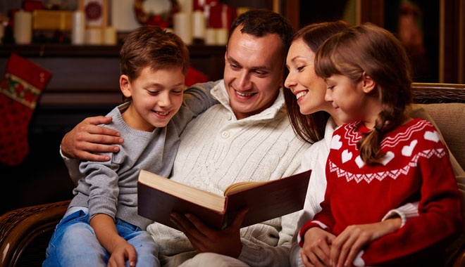 Cheerful family of four reading together on Christmas evening