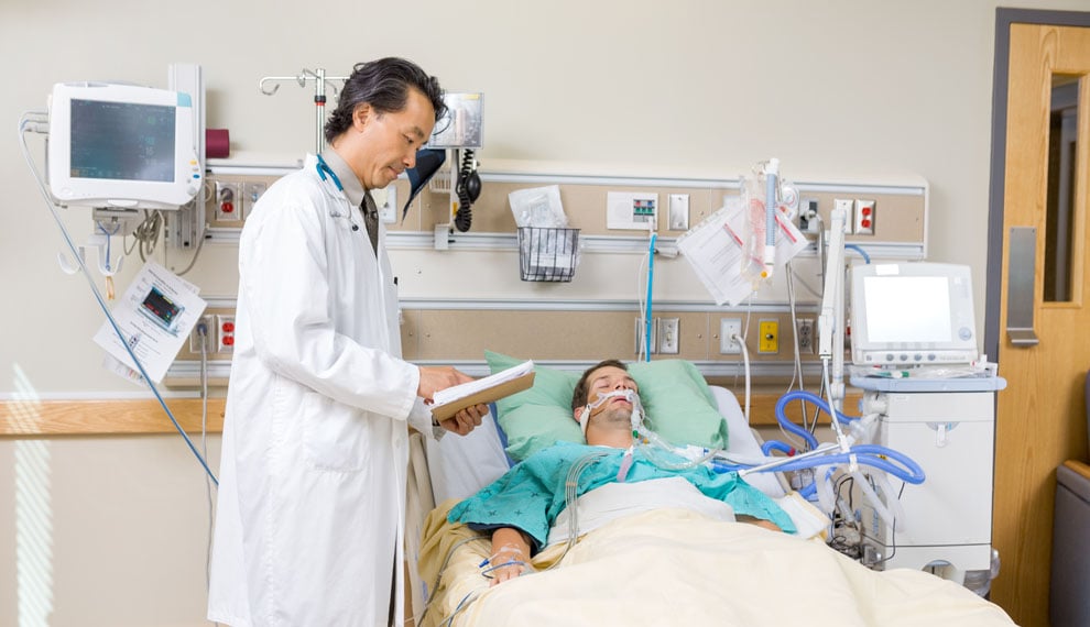 Mid adult doctor with clipboard examining patient's report in hospital room